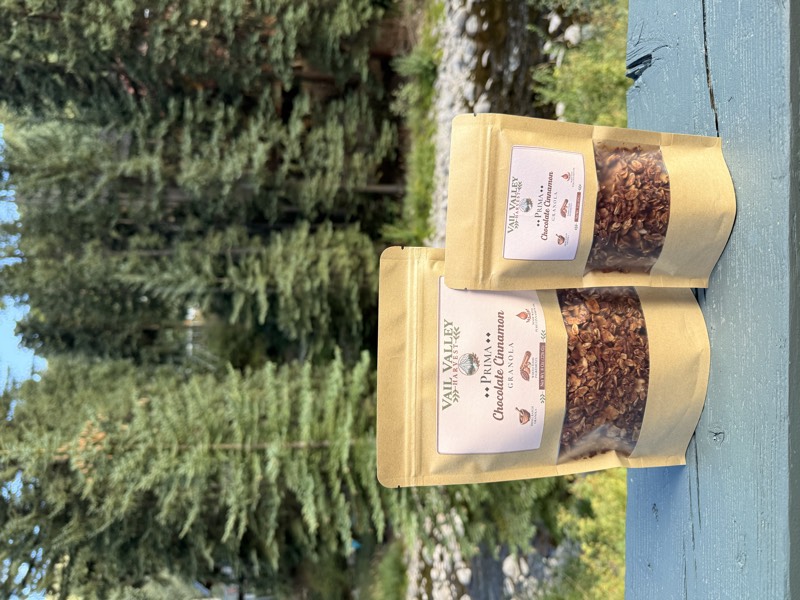 Prima Chocolate Cinnamon granola pouches in front of Vail pines